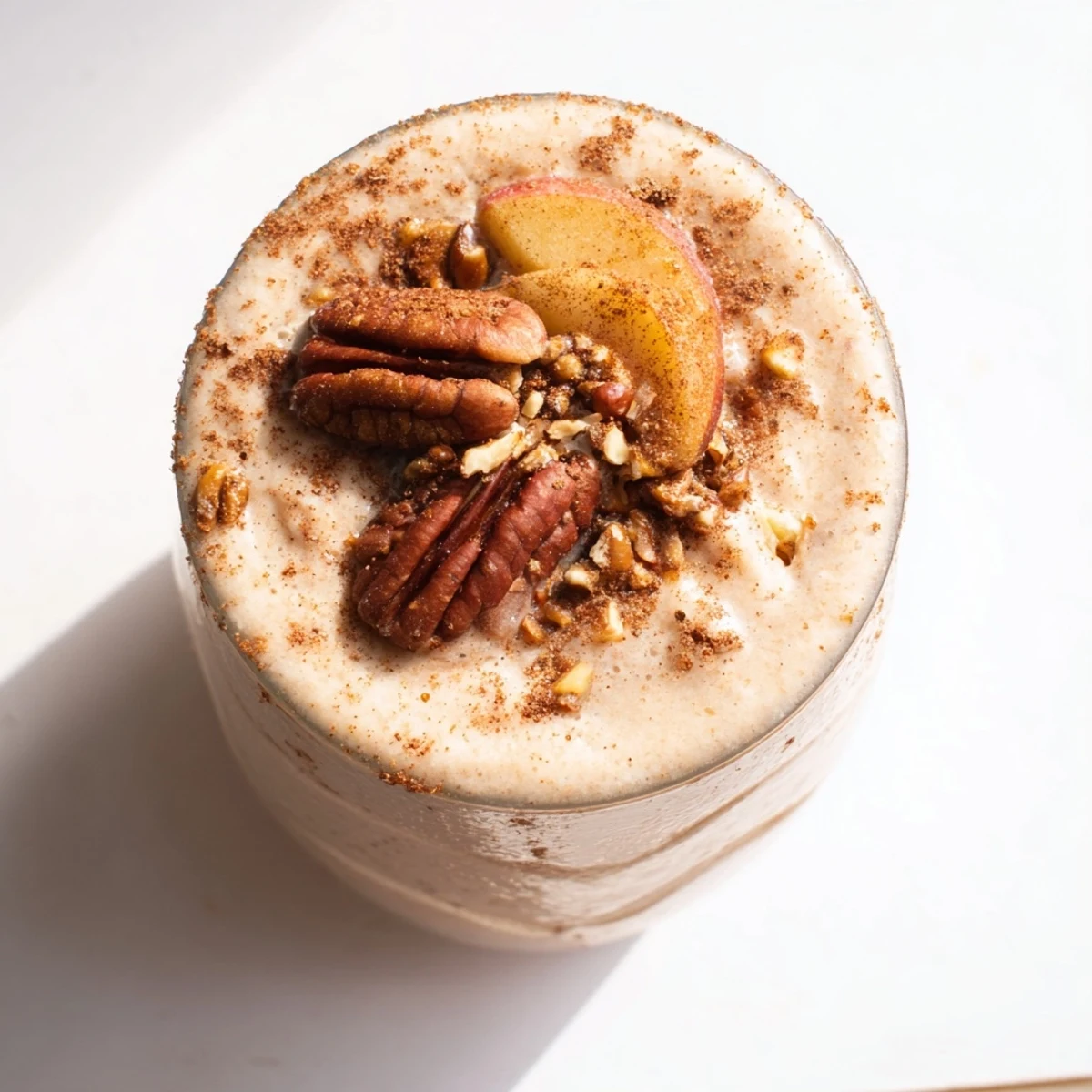 Warm, spiced Fireside Vegan Smoothie in a tall glass, garnished with walnuts and cinnamon.