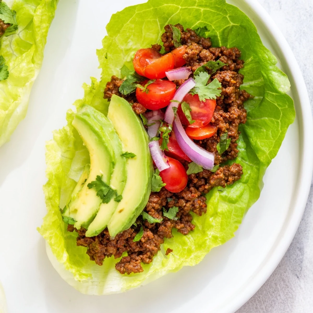 Warm Hearth Paleo Tacos featuring seasoned ground beef, diced tomatoes, and creamy avocado slices in crisp romaine lettuce cups.