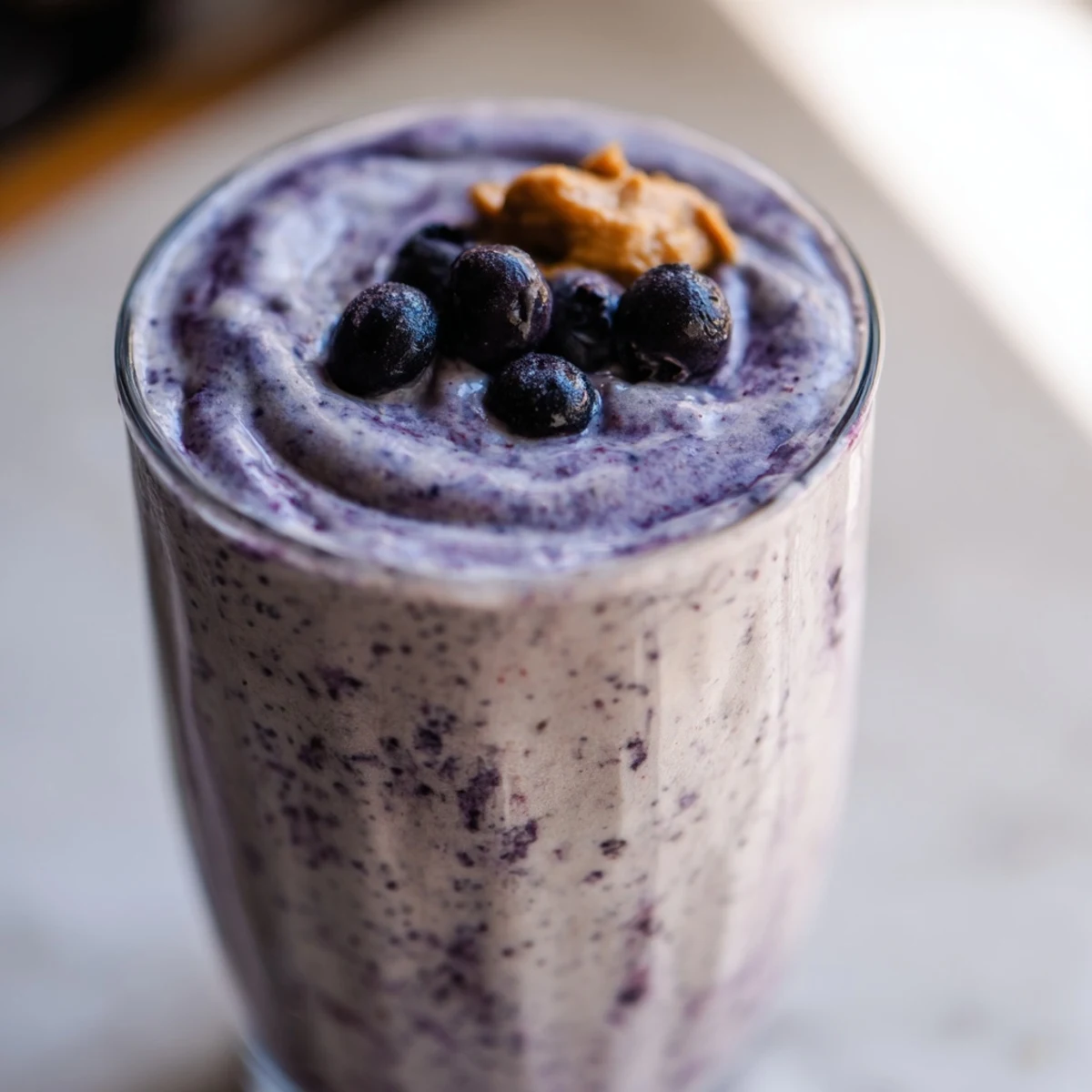 A refreshing Frosty Morning Keto Smoothie blended with almond milk and frozen avocado, served with a straw on a sunny kitchen counter.