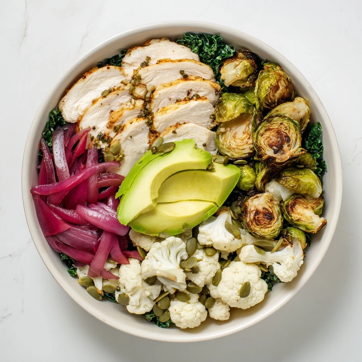 Roasted chicken and golden vegetables in a warm Winter Wellness Keto Bowl topped with avocado and pumpkin seeds.