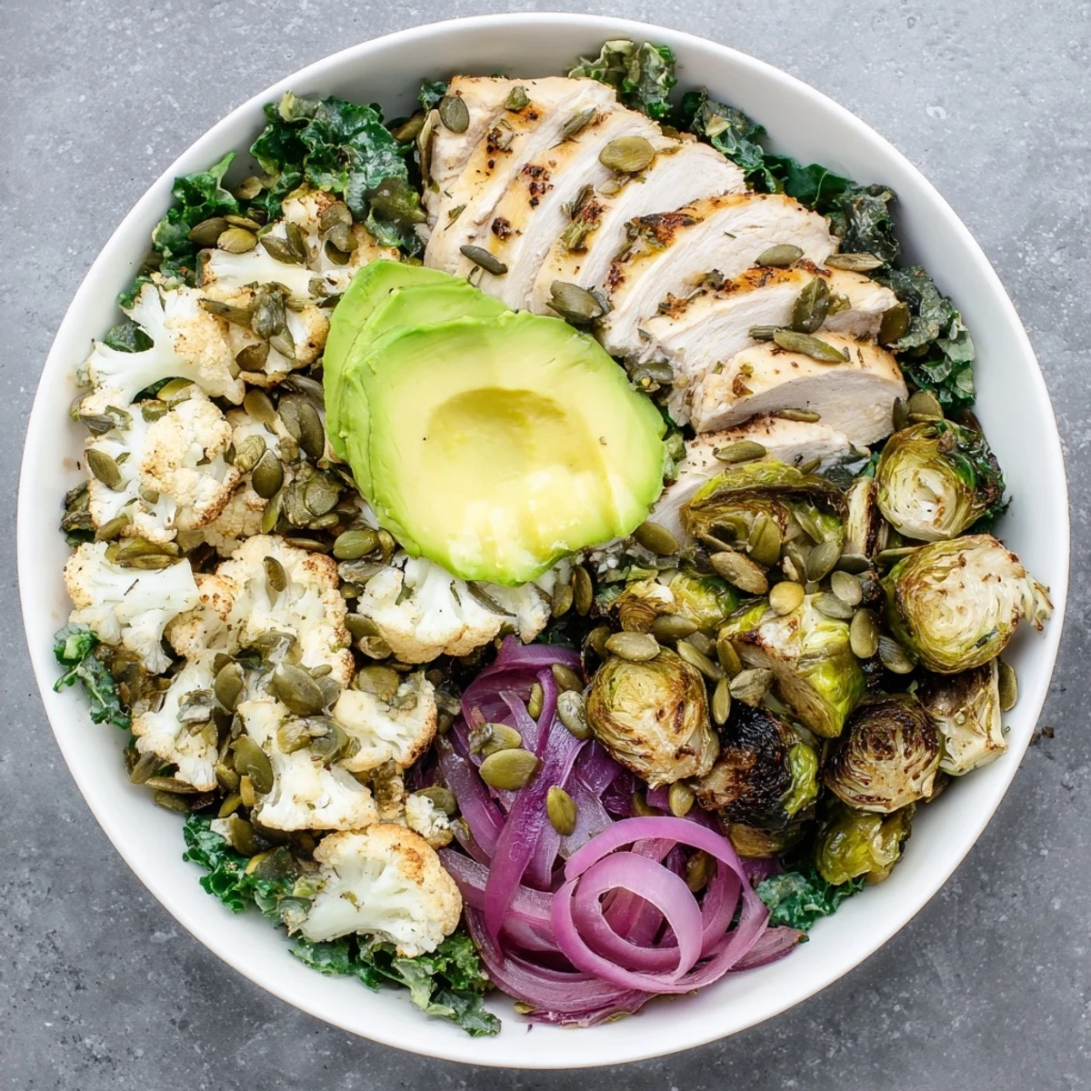 Golden roasted cauliflower and Brussels sprouts fill this Winter Wellness Keto Bowl, served with kale, chicken, and a zesty lemon dressing.