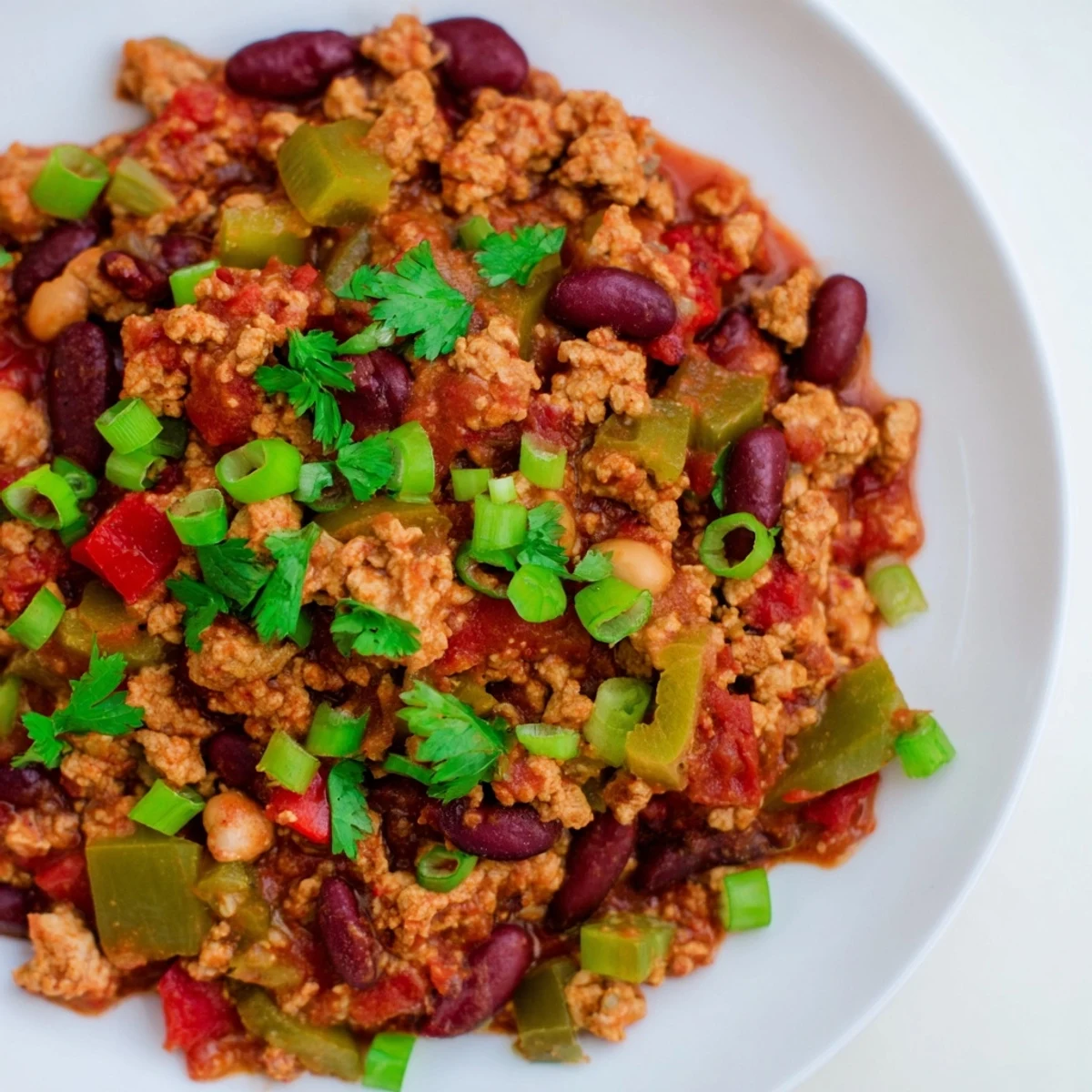 Hearty Snowy Day Low Fat Chili simmering in a pot, with colorful diced peppers, beans, and savory spices.