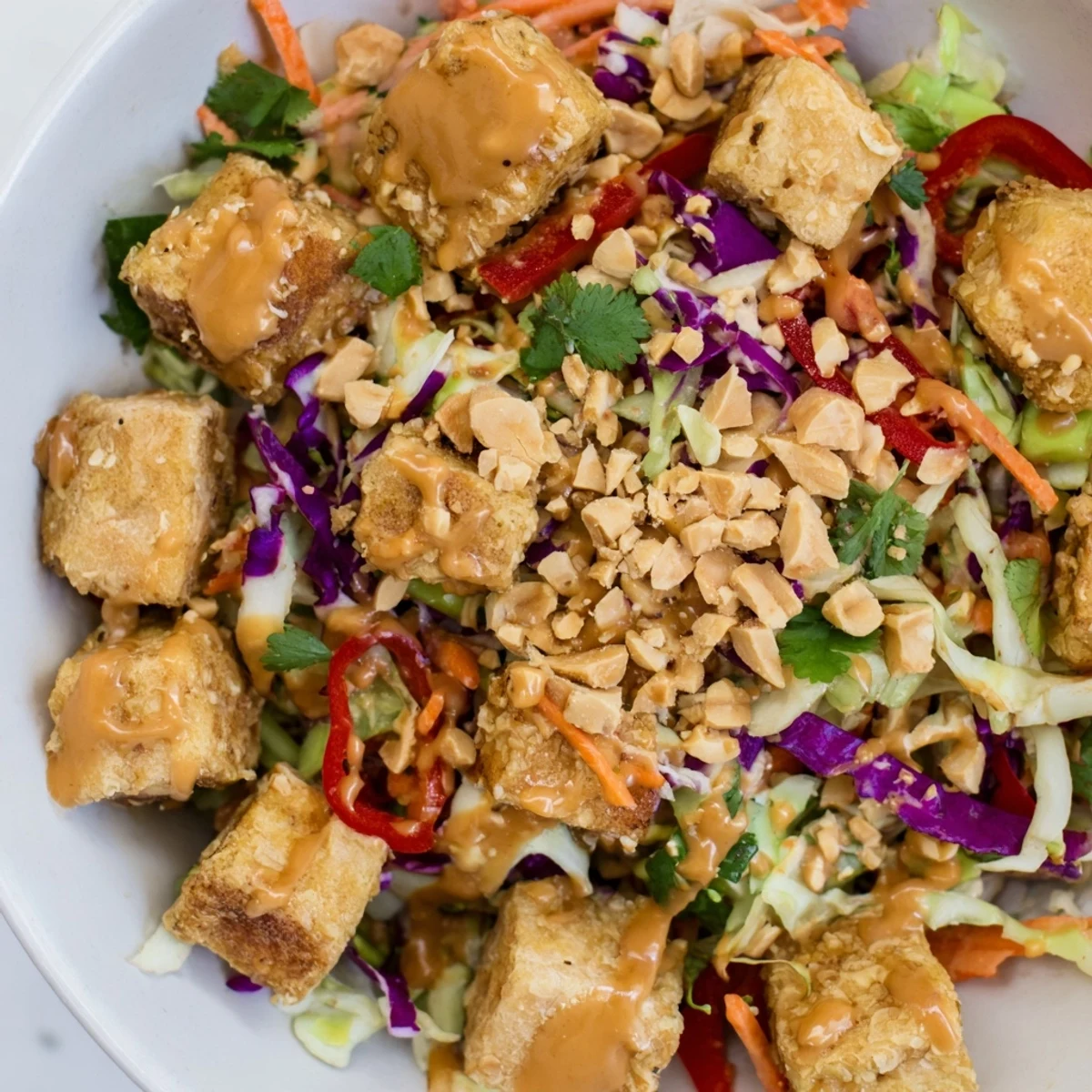 Crispy tofu cubes and vibrant shredded cabbage in a bowl of Spicy Peanut Tofu and Cabbage Crunch Bowl. 