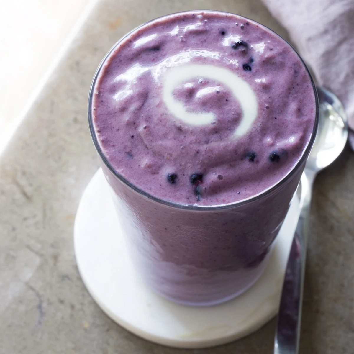 Creamy blueberry almond butter protein smoothie in a chilled glass, topped with fresh berries and sliced almonds.