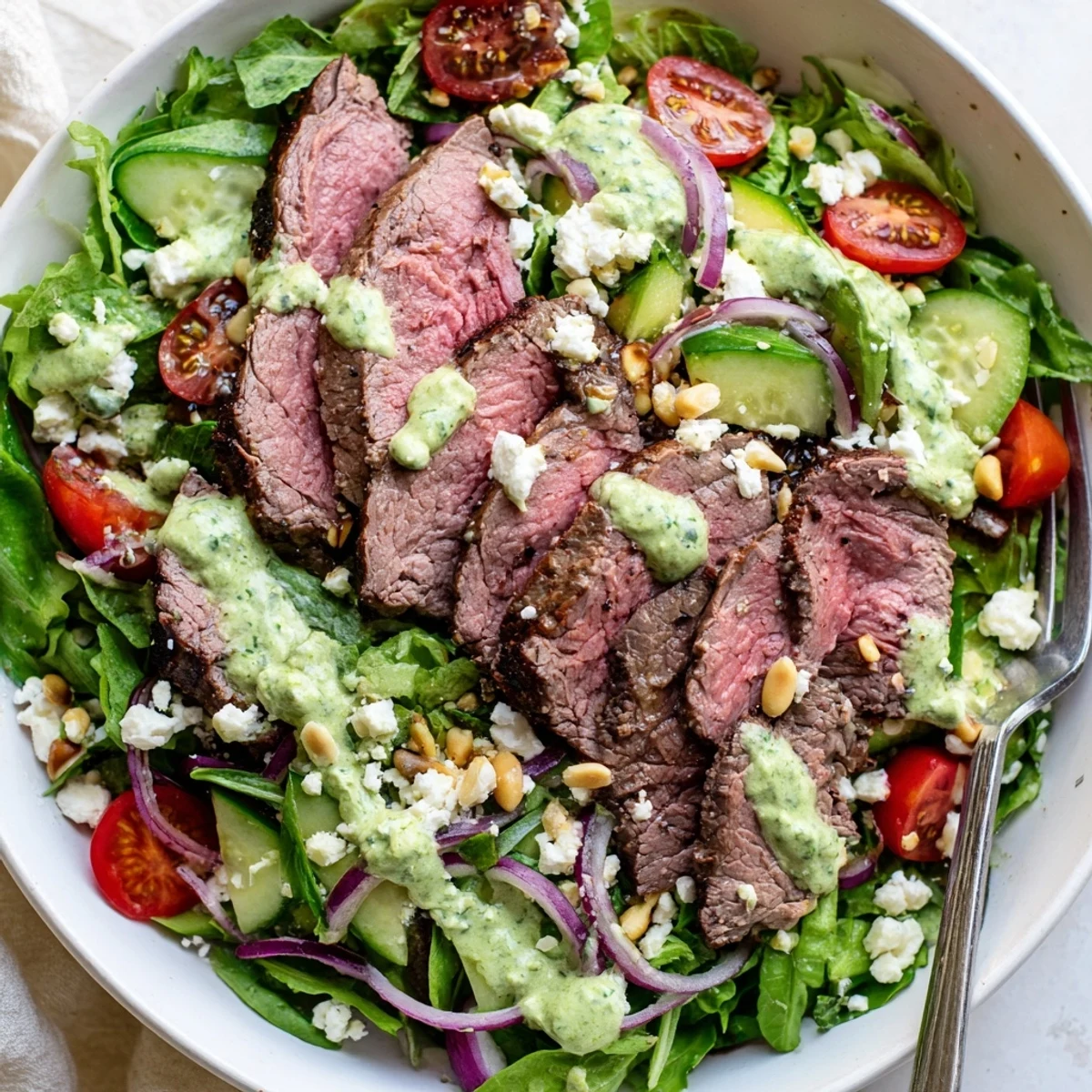 This Garlic Herb Steak Salad With Avocado Lime Dressing features bright cherry tomatoes, cucumber, and feta cheese, ready for a zesty drizzle.