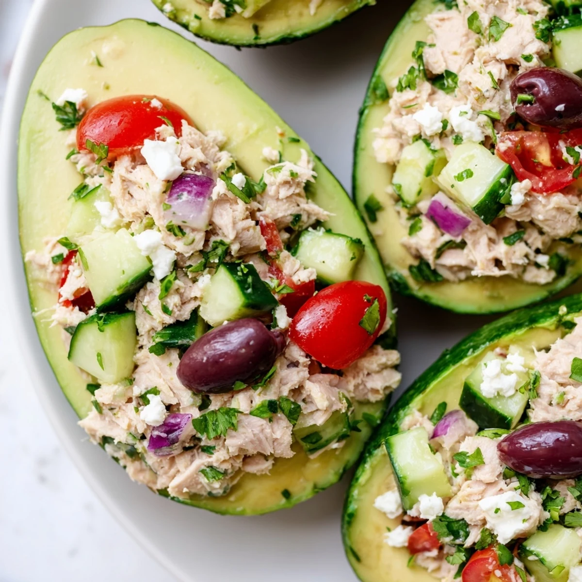 Ripe avocado bowls filled with light Mediterranean tuna and cucumber mixture for lunch