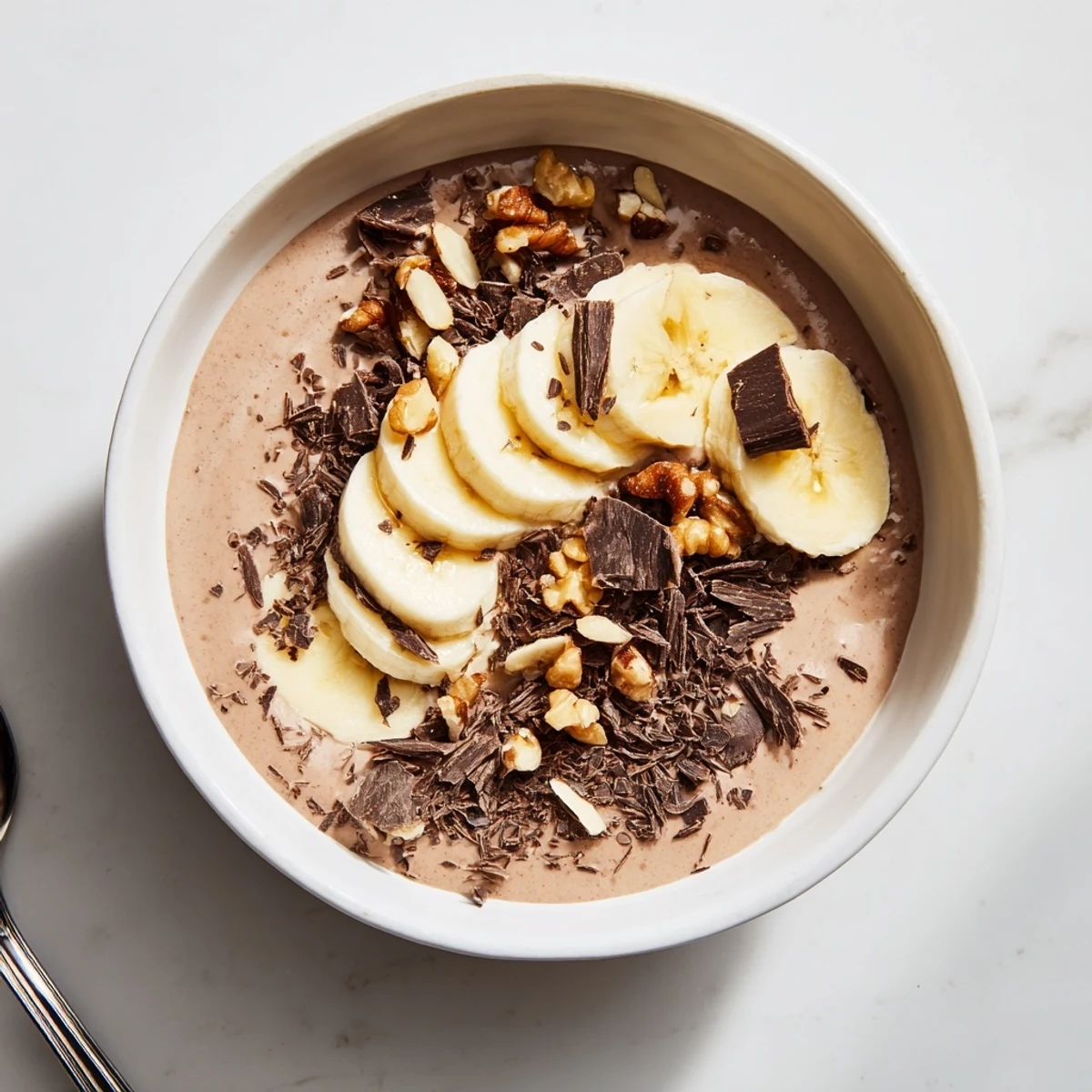 Rich chocolate banana protein chia pudding garnished with chopped nuts and cocoa powder on a wooden table
