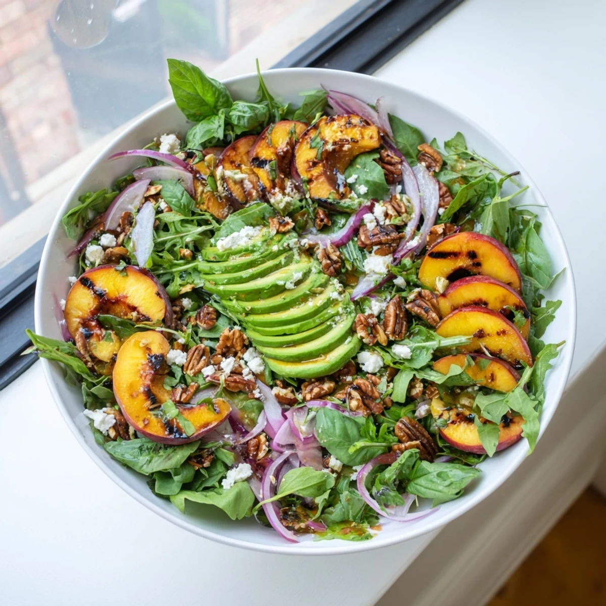 Fresh grilled peach and avocado salad with peppery arugula, crunchy pecans, and tangy honey-lime dressing