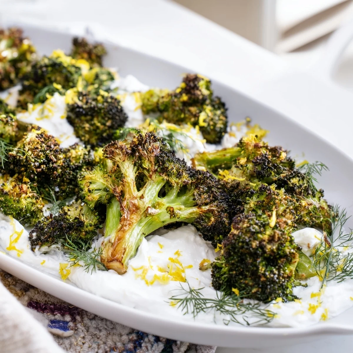 Crispy roasted broccoli served atop fluffy lemon feta dip sprinkled with herbs and pepper