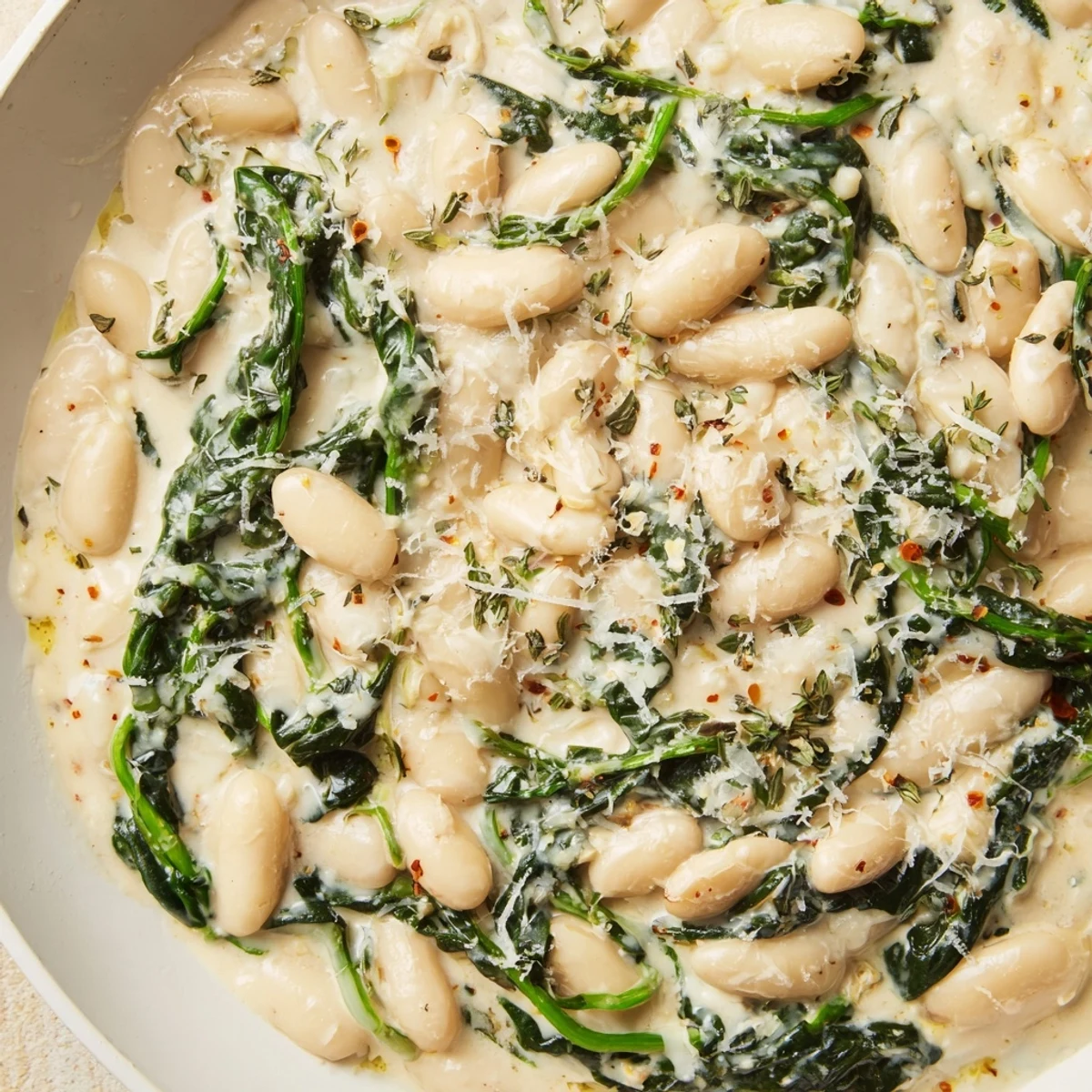 Golden white beans and fresh spinach swimming in a rich, velvety cream sauce in a skillet