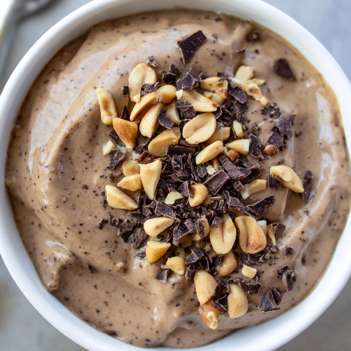 Velvety chocolate peanut protein chia whip pudding garnished with banana slices and chocolate shavings for a nutritious high-protein snack