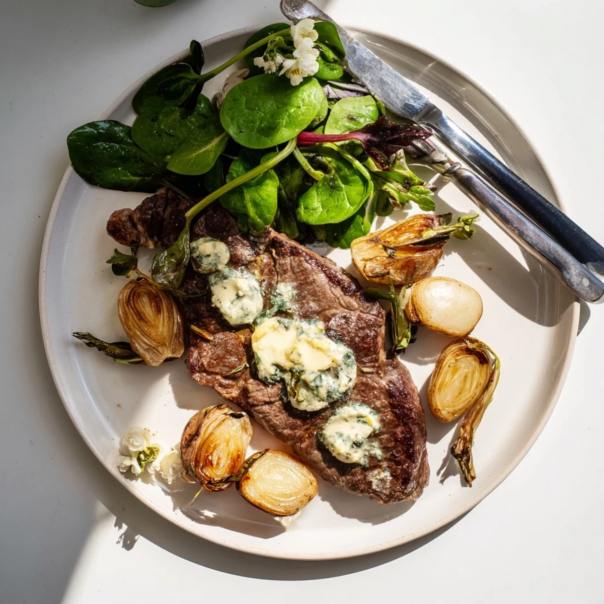Golden seared steak with aromatic garlic butter served alongside caramelized radishes and vibrant baby greens