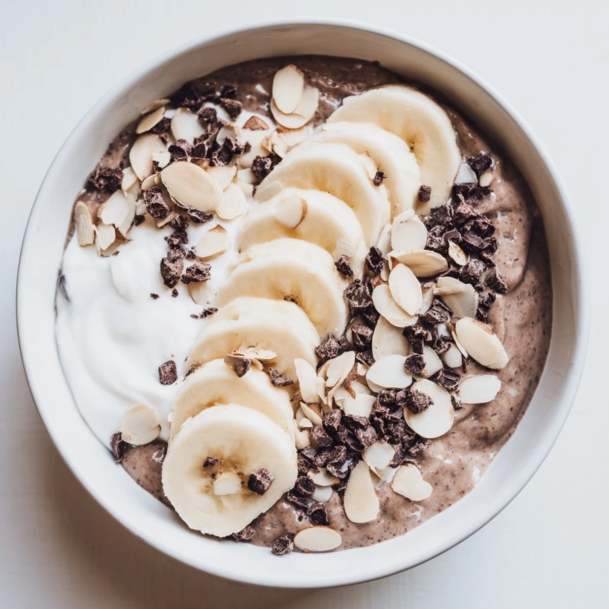 Creamy chocolate banana almond protein chia bowl topped with fresh banana slices and crunchy almonds