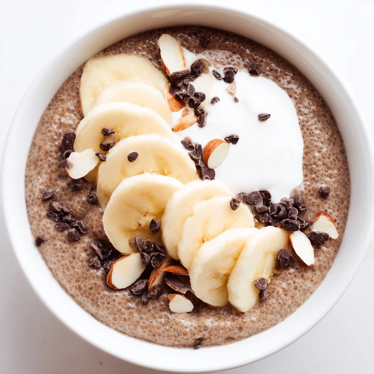 Protein-packed breakfast bowl featuring chocolate chia pudding layered with bananas, almonds, and dark chocolate chips