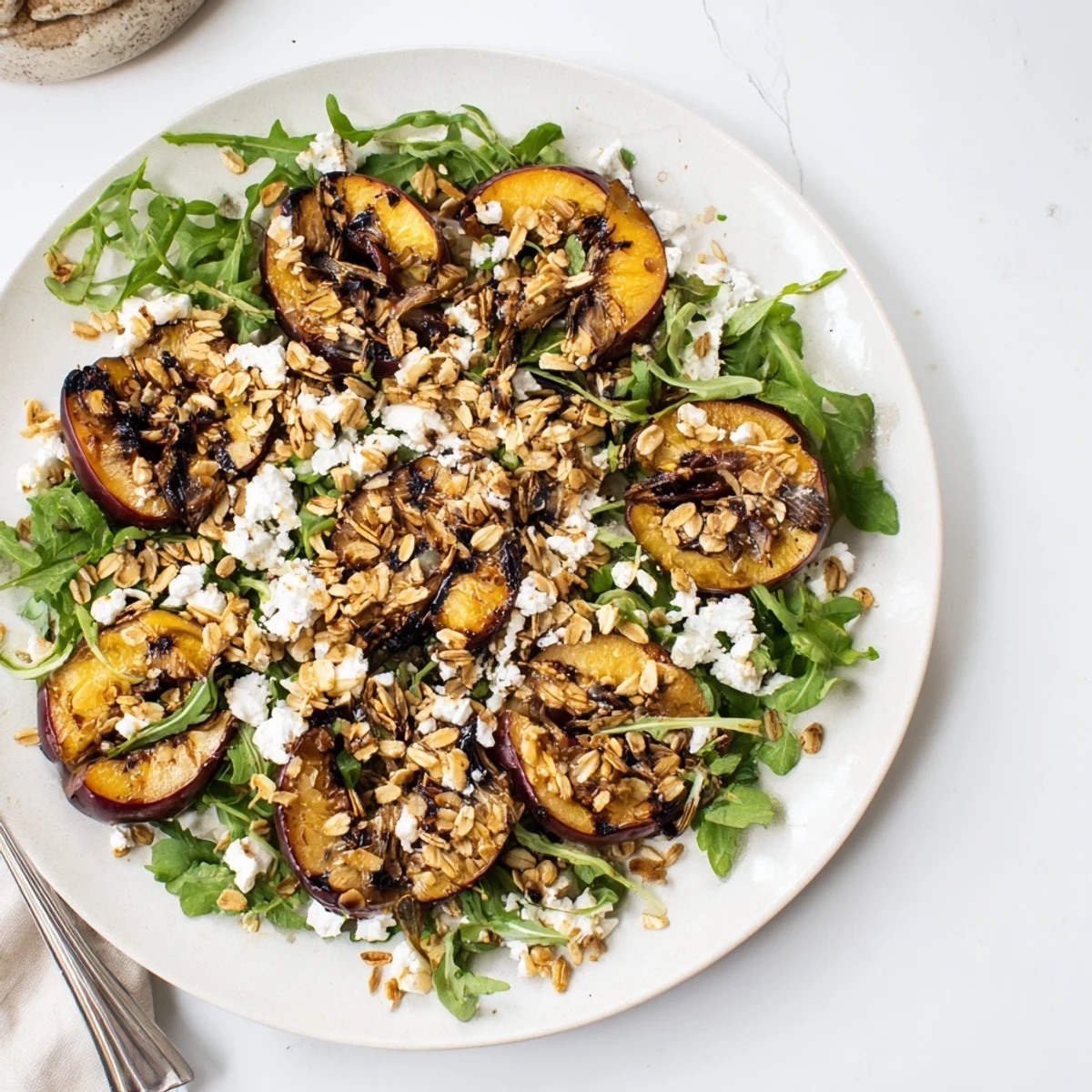 Elegant plated salad with sweet grilled plums, fresh arugula, crumbled cheese, and honey almonds