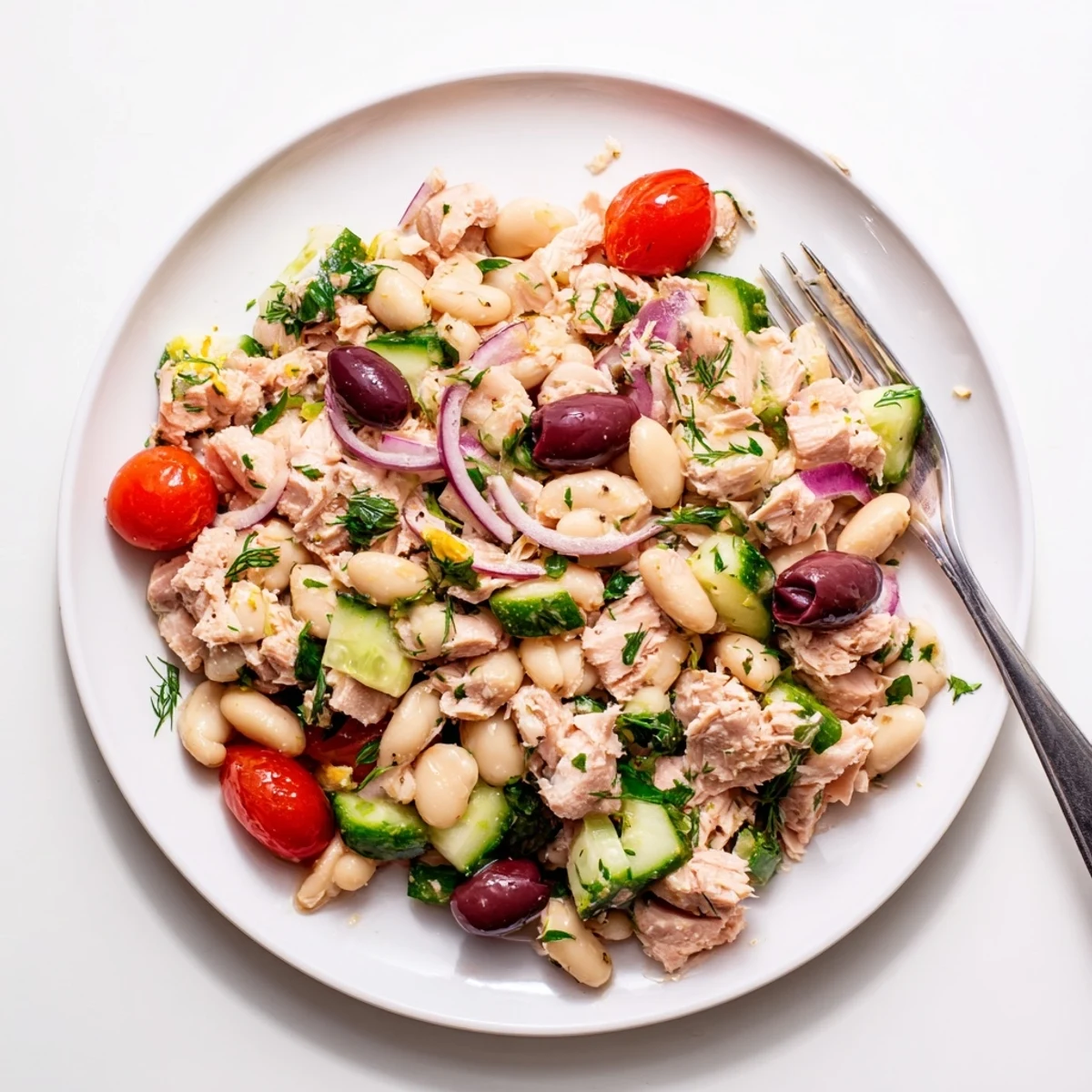 Colorful Mediterranean tuna and white bean herb salad with fresh vegetables and olives in a serving bowl