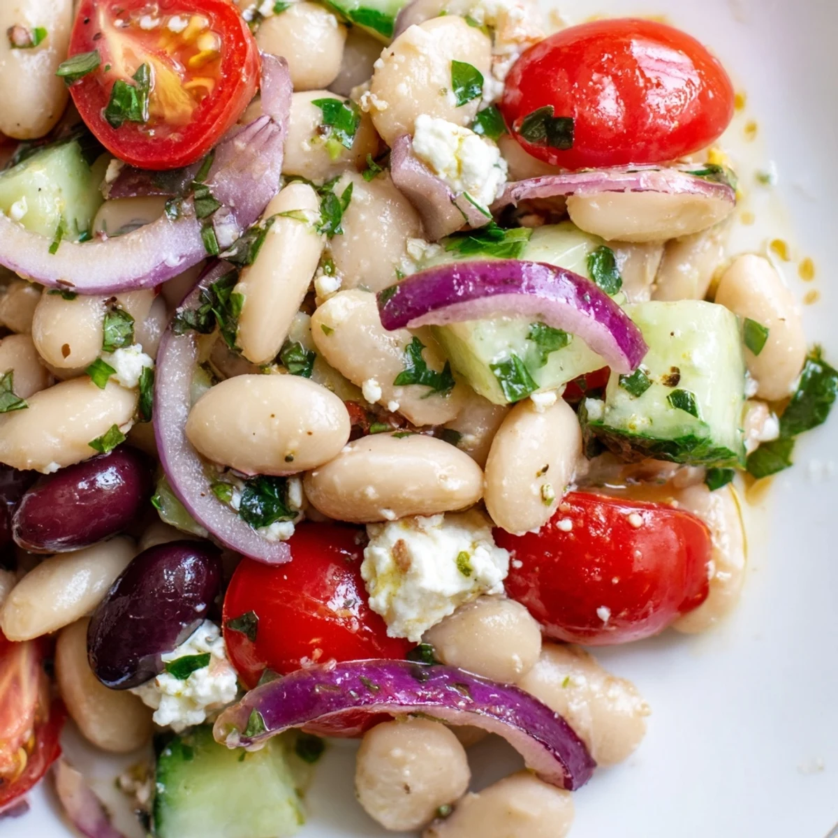 Mediterranean White Bean and Tomato Herb Toss served in a rustic bowl with fresh basil leaves and lemon wedges