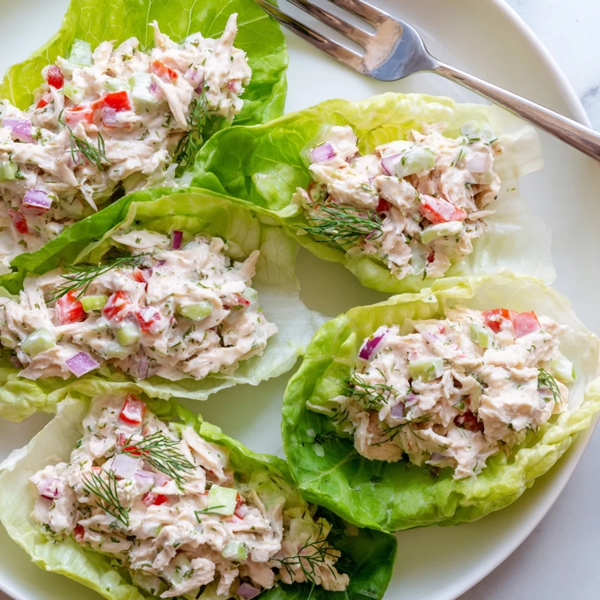 Cottage cheese dill chicken salad lettuce wraps garnished with fresh herbs on a rustic plate