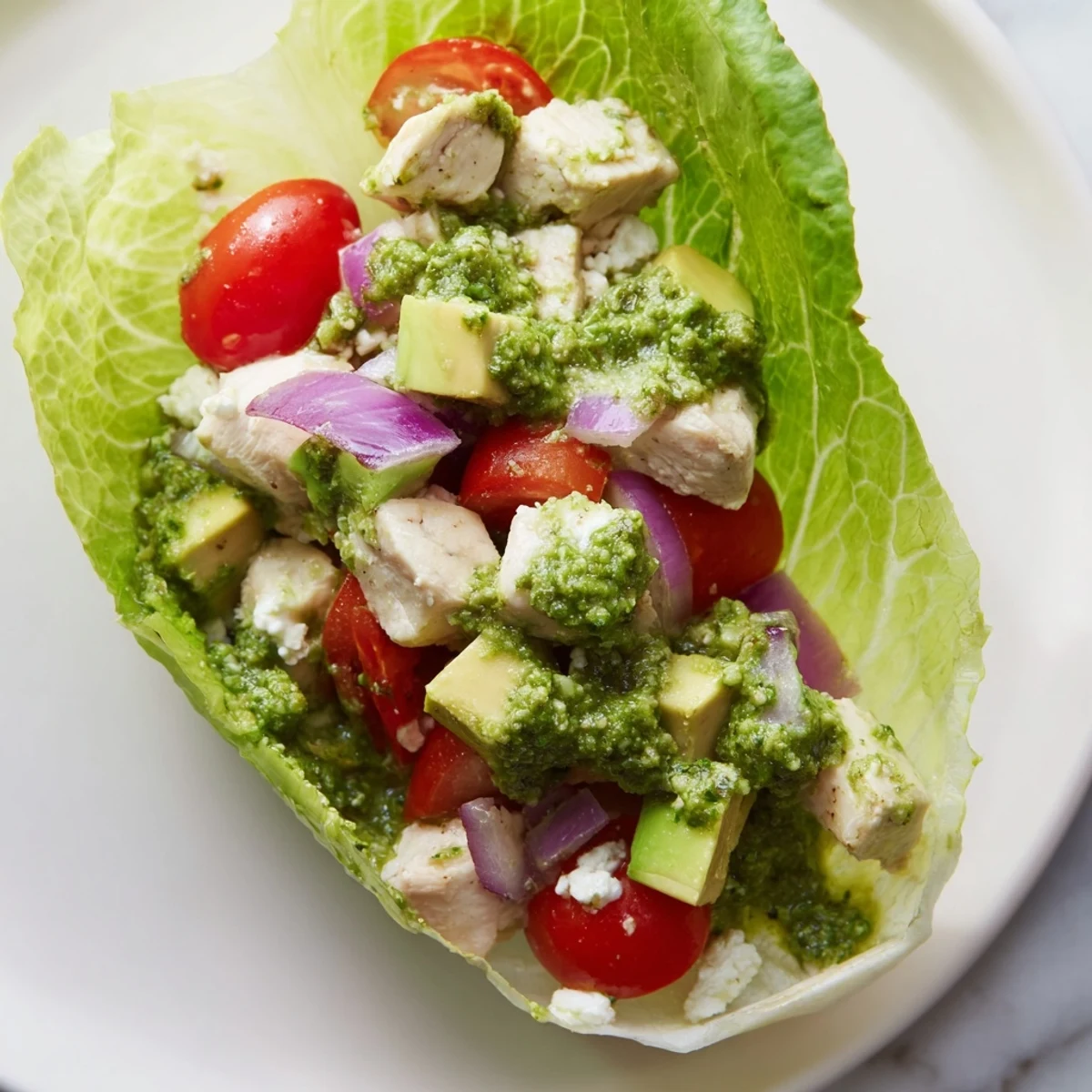 Crisp butter lettuce cups overflowing with cottage cheese avocado pesto chicken and bright green herbs