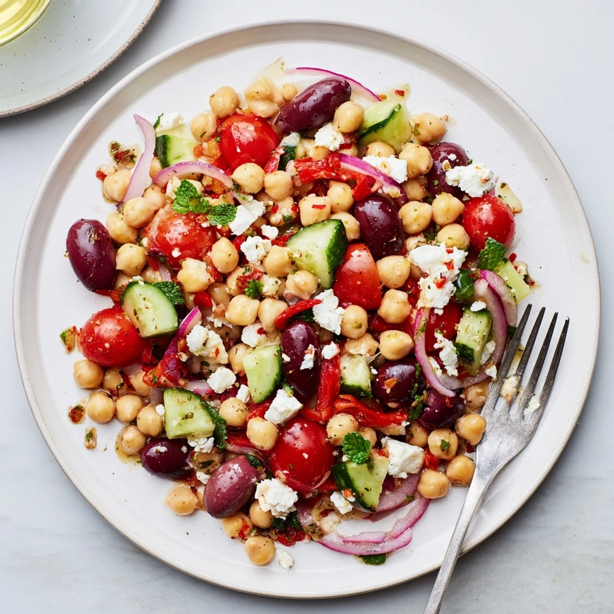 Close-up of Mediterranean chickpea and tomato olive salad in a white serving bowl with pita
