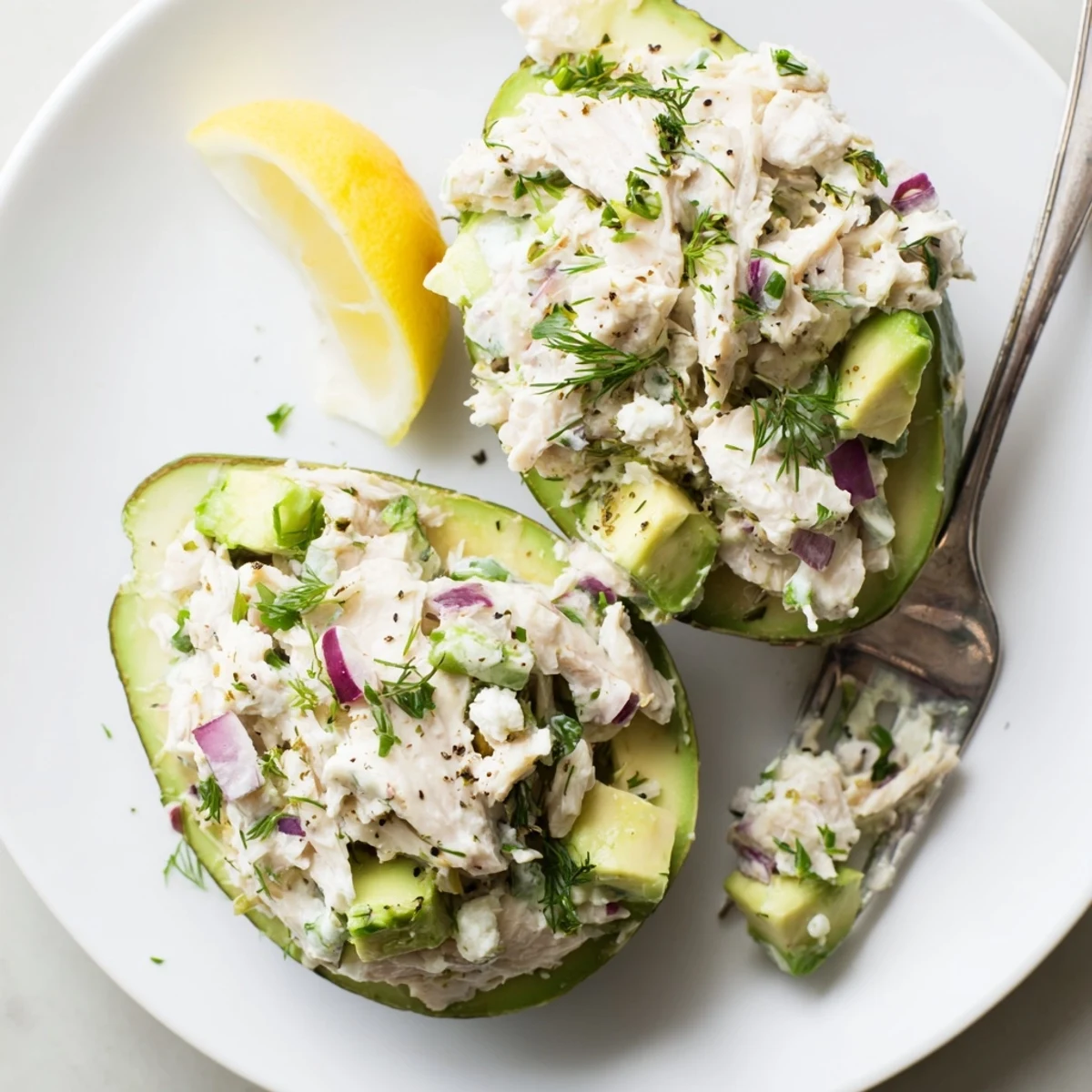 Cottage Cheese Herb Chicken Salad Stuffed Avocados topped with chopped chives, lemon wedge