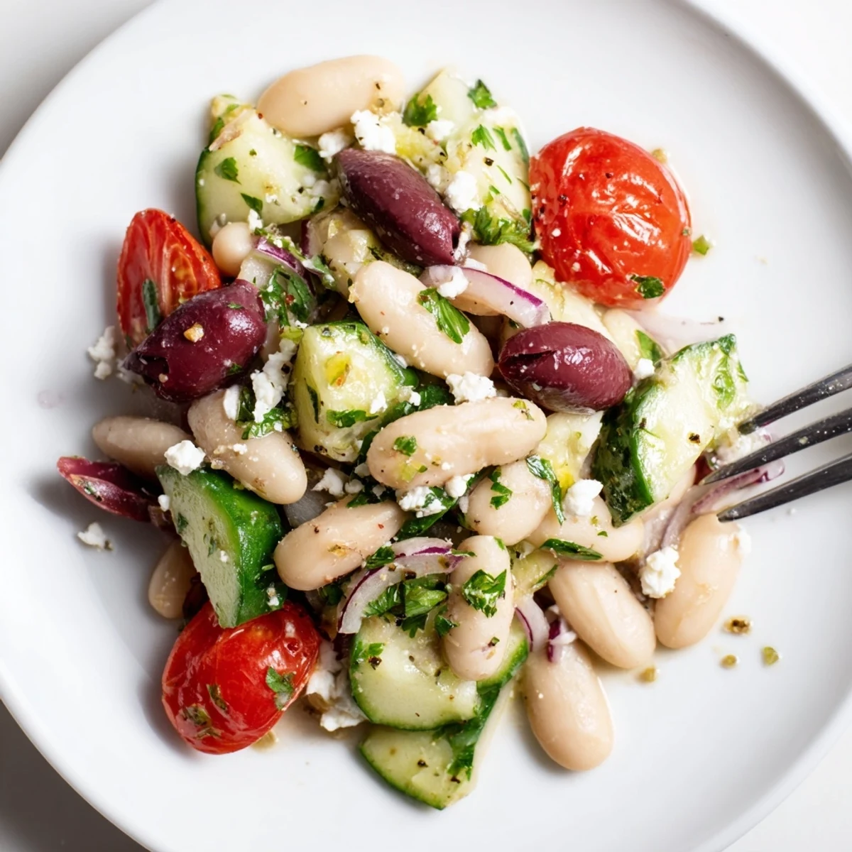 Mediterranean White Bean and Cucumber Tomato Salad garnished with feta, herbs, olive oil