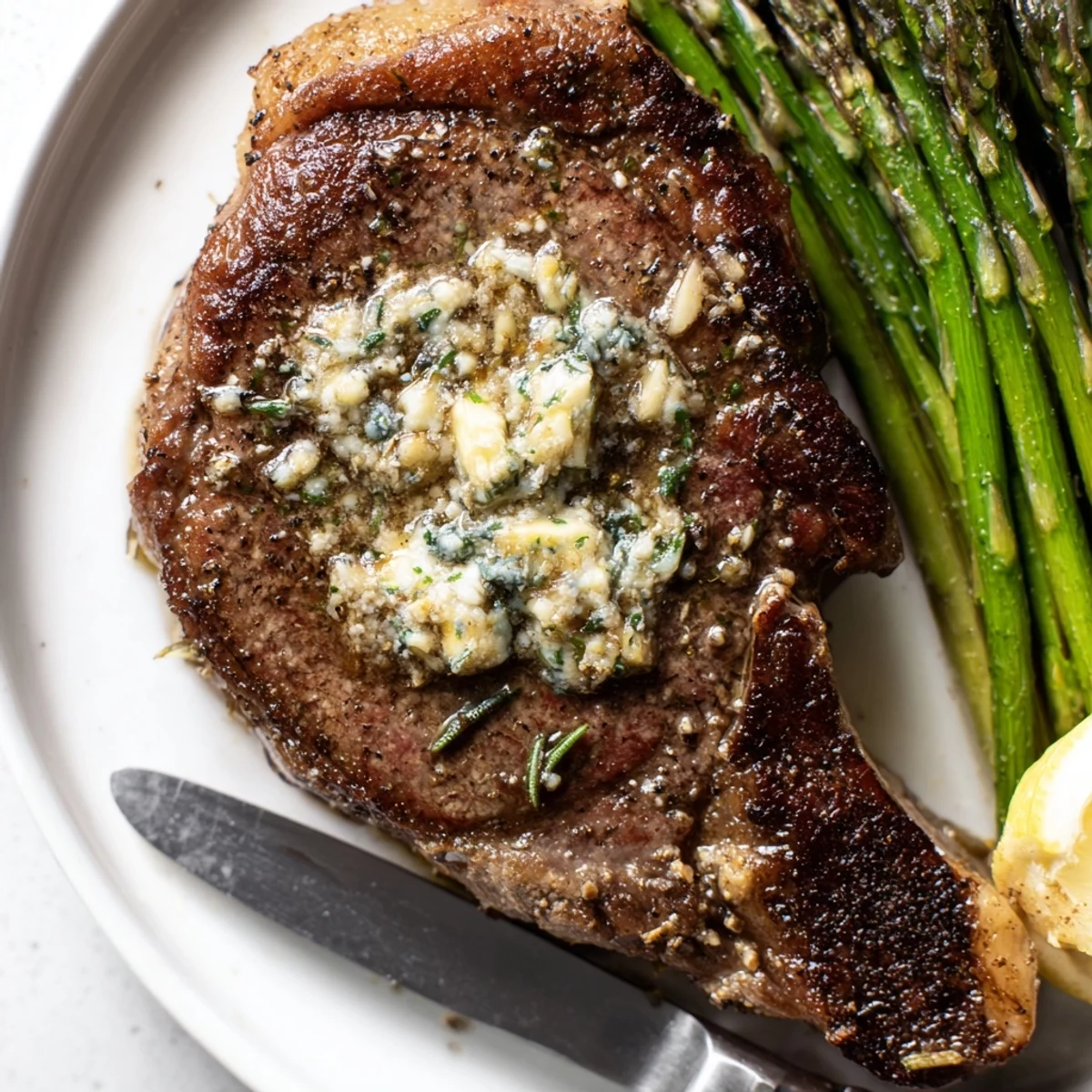 Garlic Herb Steak With Roasted Asparagus on plate, butter-glazed crust, lemon wedge  