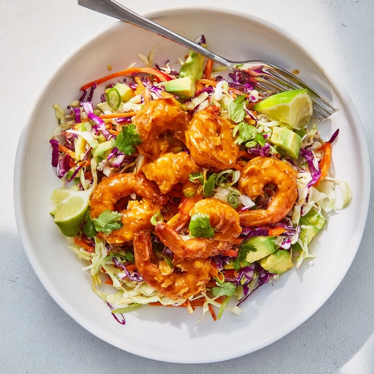 Juicy shrimp coated in sweet and spicy mango sauce resting atop crunchy purple green cabbage slaw