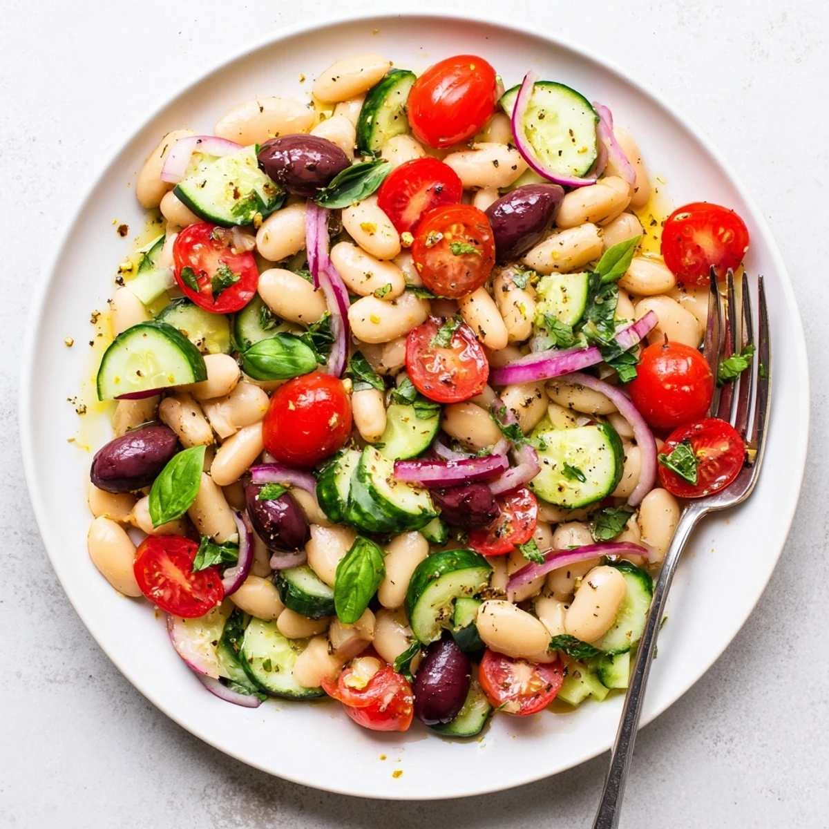 Creamy white beans tossed with juicy tomatoes crisp cucumber and fragrant basil in a zesty Mediterranean dressing