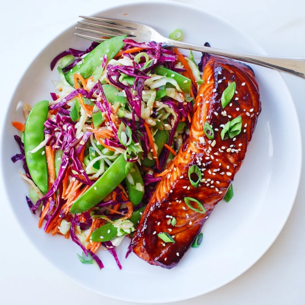 Baked Miso Ginger Salmon with glossy umami marinade served over a crisp vegetable slaw tossed in nutty sesame dressing and topped with toasted seeds
