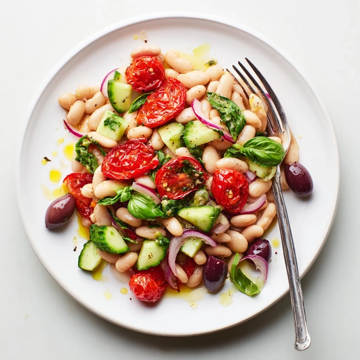 Fresh Mediterranean white bean and roasted tomato basil salad featuring bright red tomatoes and torn green basil leaves