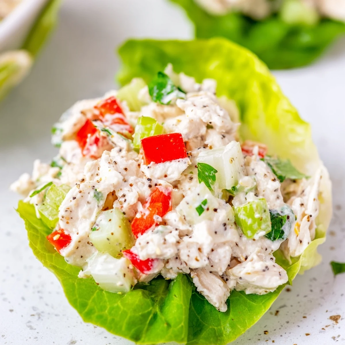 Crisp butter lettuce cups filled with creamy cottage cheese lemon pepper chicken salad topped with colorful diced vegetables