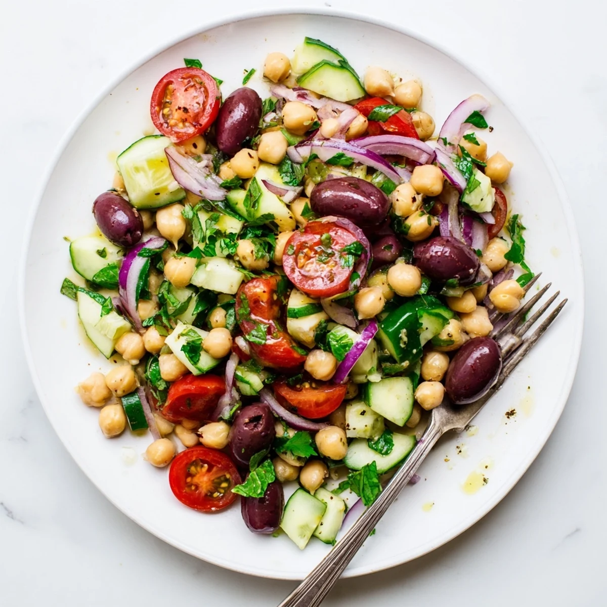 Colorful Mediterranean chickpea salad bowl with tomatoes, cucumber, and fresh basil leaves