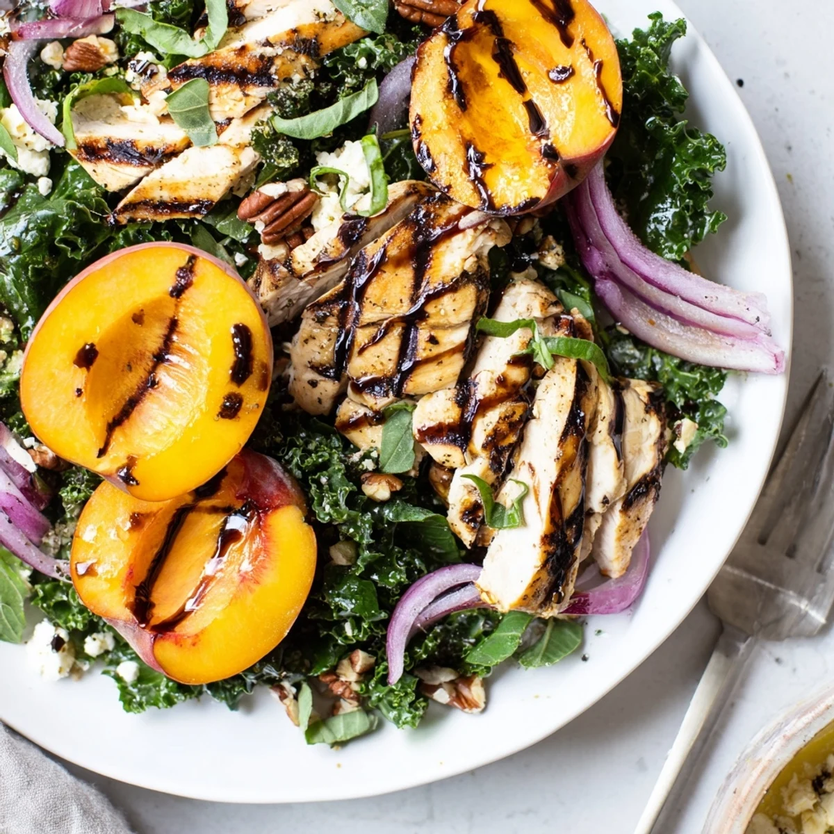 Juicy grilled peaches top Grilled Peach and Kale Chicken Salad with Fresh Basil.