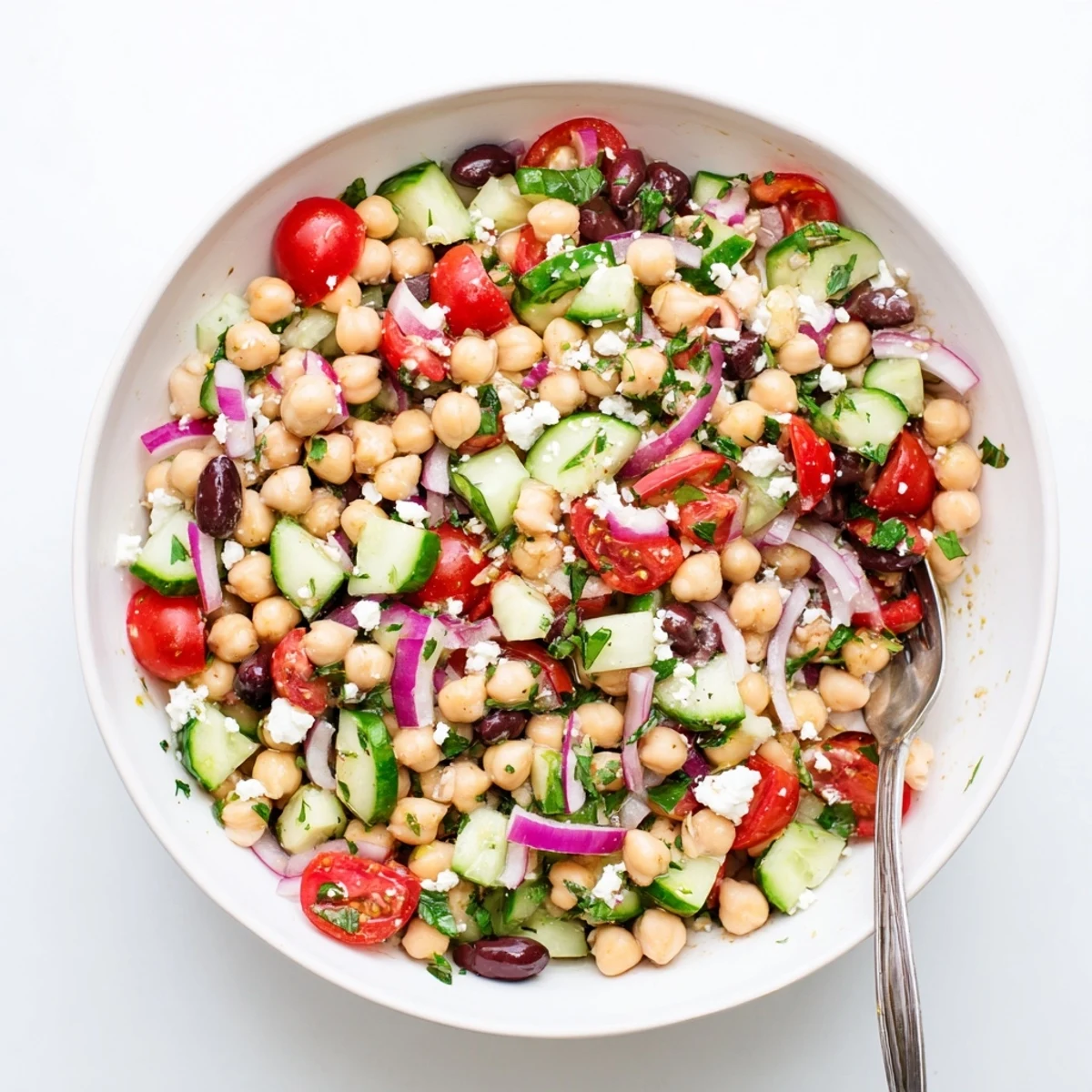 Fresh Mediterranean chickpea salad with juicy tomatoes, crisp cucumber, and fragrant basil in a white serving bowl