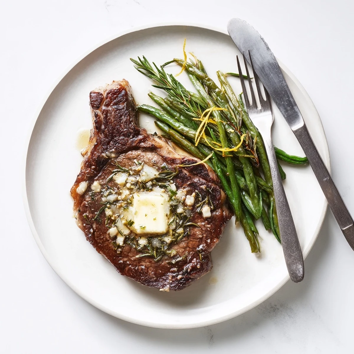 Juicy garlic herb steak resting alongside tender roasted green beans with fresh lemon wedges