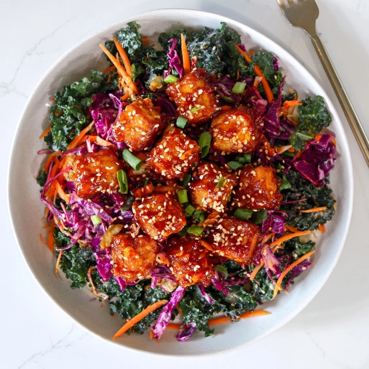 Crispy chili garlic tofu with sesame kale slaw plated on rustic white dish