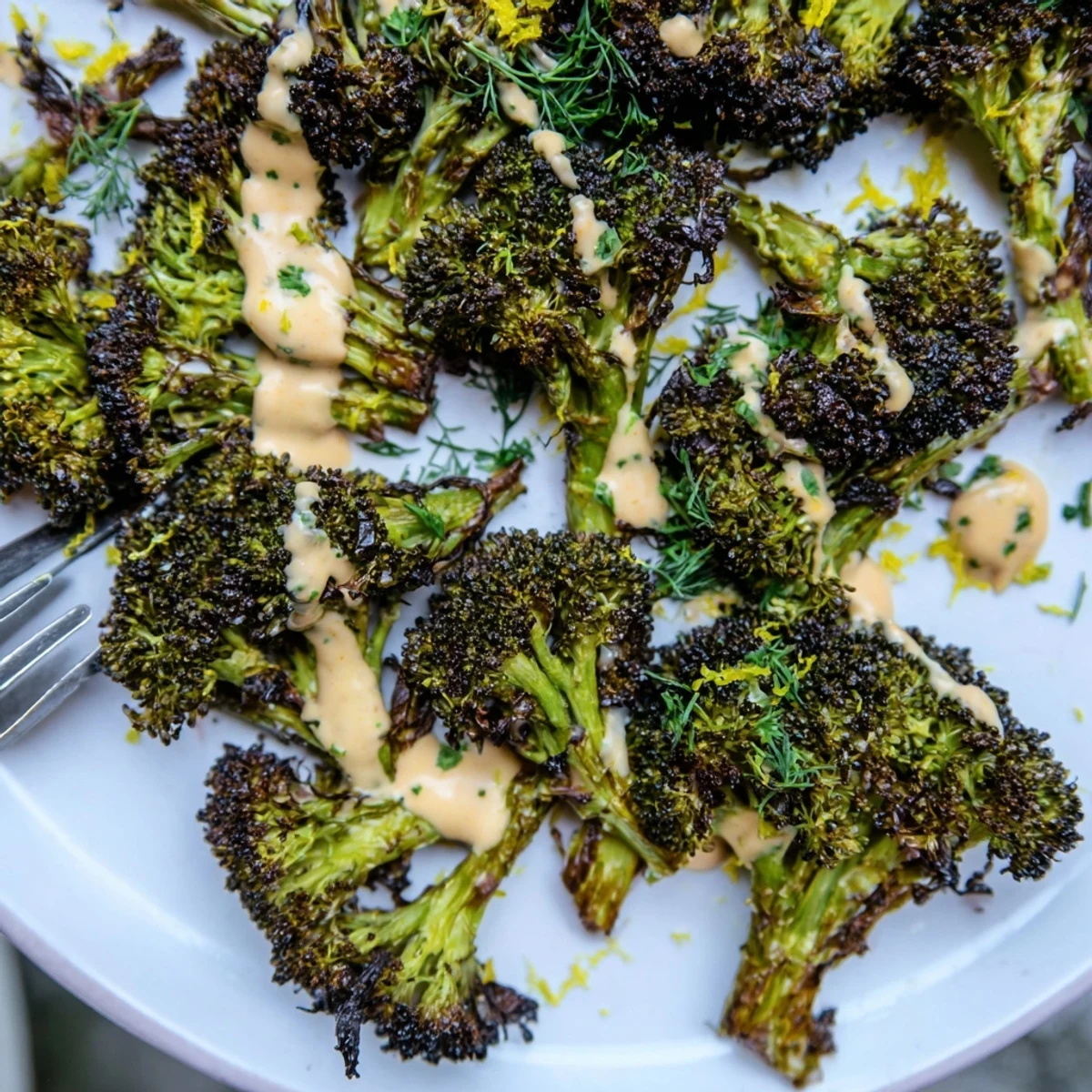 Crispy roasted broccoli with lemon herb tahini drizzle served on a rustic white platter