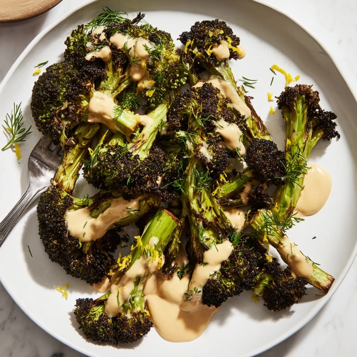 Golden roasted broccoli florets generously coated in creamy lemon herb tahini drizzle sauce
