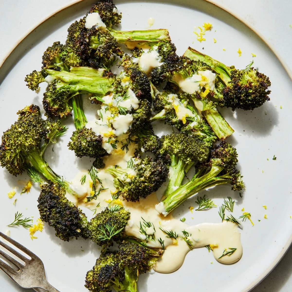 Tender charred broccoli crowned with vibrant green lemon herb tahini drizzle and fresh herbs