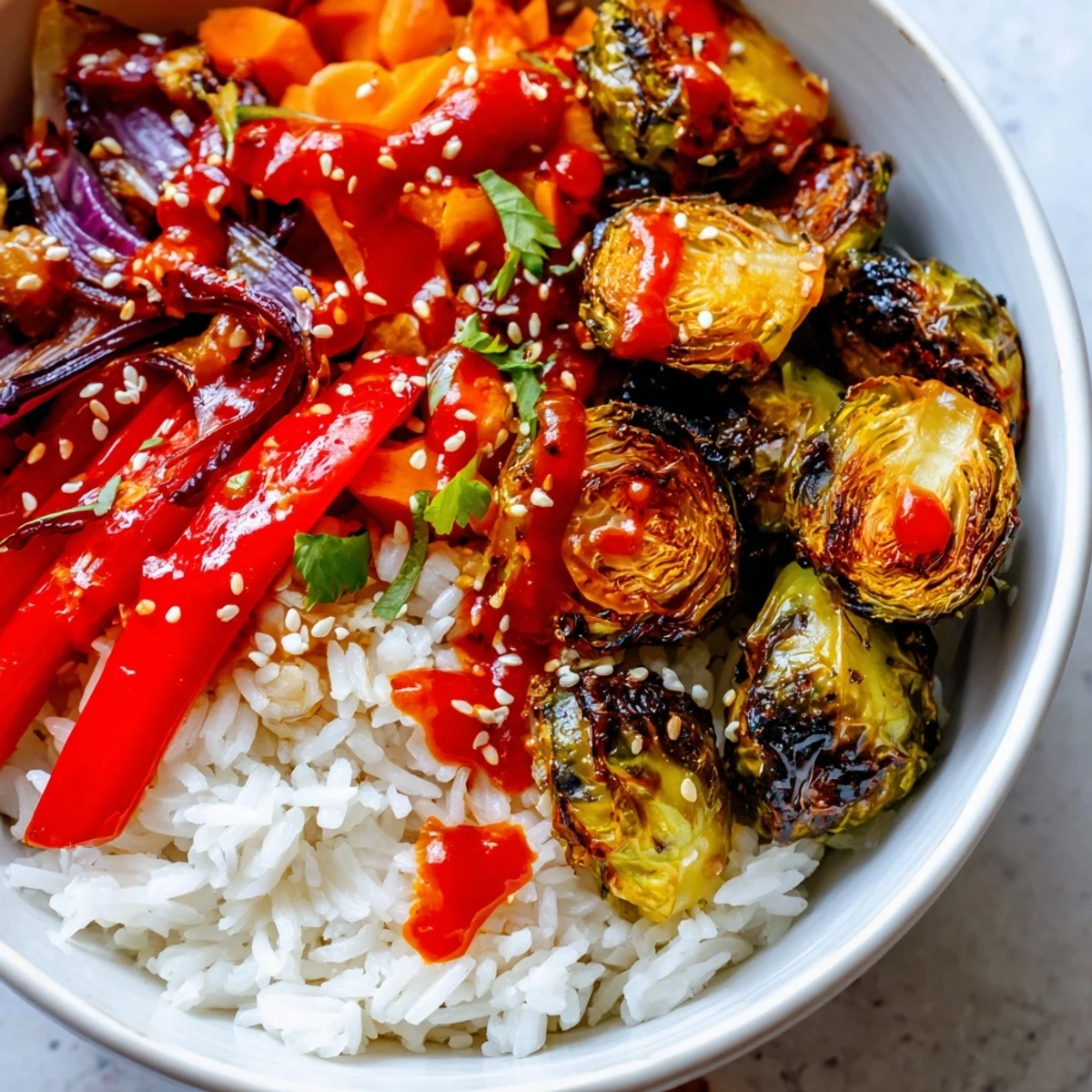 Spicy chili crisp roasted Brussels sprout veggie bowl glistening with sesame seeds over fluffy white rice