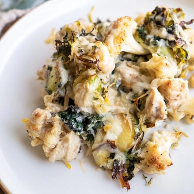 The creamy Winter Garden Keto Casserole is served on a white plate alongside a crisp green salad.