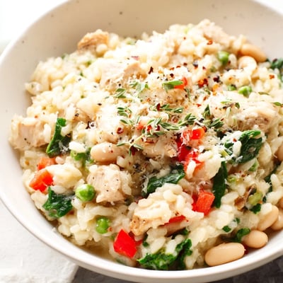 Festive Holiday Market High Protein Risotto with tender chicken, peas, and bell pepper, paired with a glass of white wine.