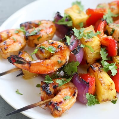 Spicy and sweet Grilled Pineapple and Shrimp Skewers served over fluffy rice with lime wedges.