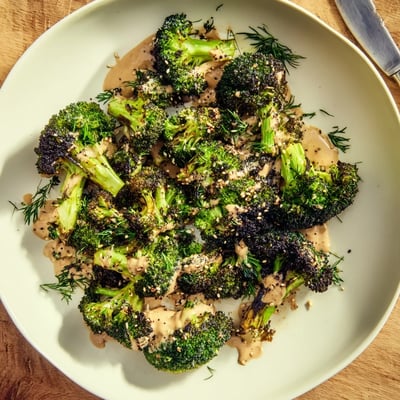 Warm Roasted Broccoli With Lemon Herb Tahini Sauce served with toasted sesame seeds