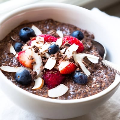 Thick chocolate almond coconut berry protein chia cream in a glass layered with sliced almonds
