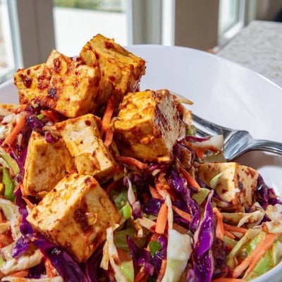 Crispy pineapple tofu served over zesty lime cabbage slaw with crushed peanut garnish